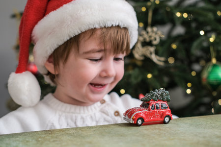 Cute little boy wearing a Santa hat happy playing with little christmas carの写真素材