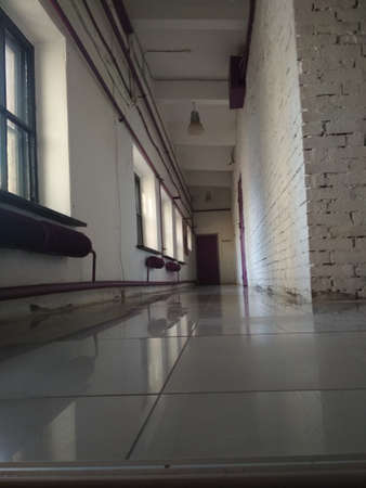 View inside the entrance corridor in front of room, old school or apartment building, dead end long and narrow walkway and glass window with early morning orange shine.の写真素材