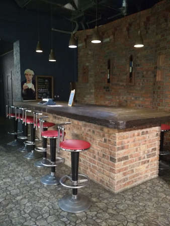 Row of tables, red seats and bar counter with red tall chairs in empty cozy restaurantの写真素材