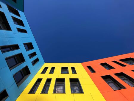 Multi-colored bright facades of the school with black window frames. Look up from the blue skyの写真素材