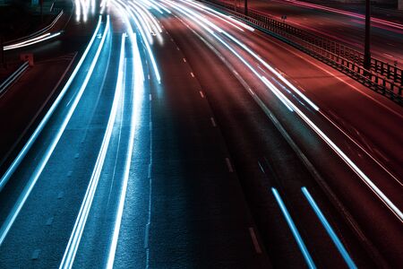 White blue and red lights of a car in motion at long exposure on a night highway. Background with...