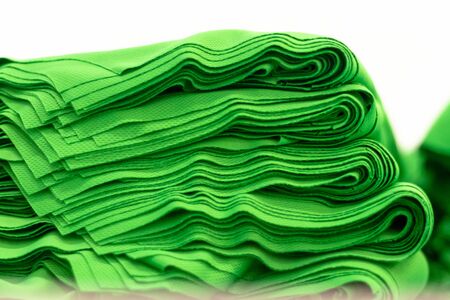 Cloth sports mesh folded into a stack of bright green color close-up. Sewing industry.