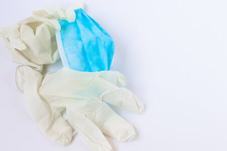 Used, infected with the virus, covid individual white disposable gloves and a medical blue mask are...