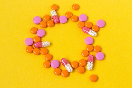 Multi-colored pills in the form of a female egg on a bright yellow background, top view. Medication for the disease for patients. Dose drugs and vitamins for health. Copy space. Close up.の写真素材
