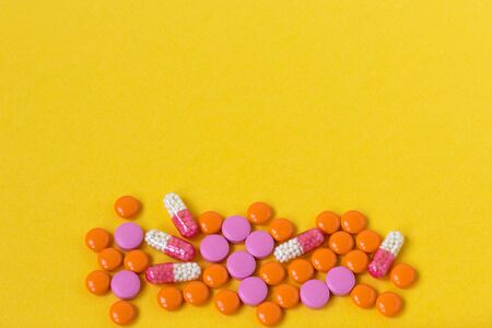 Multi-colored pills on a bright yellow background, top view. Medication for the disease for patients. Dose drugs and vitamins for health. Copy space. Close up.の写真素材