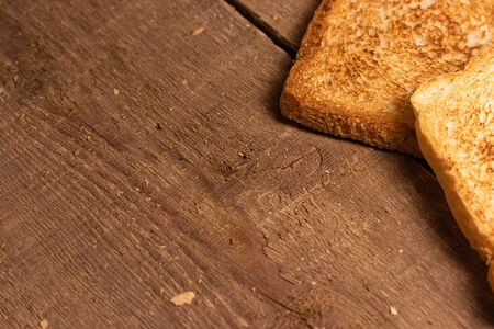 Tasty fried toast bread slices lie on a natural brown wooden background. Simple rustic style.