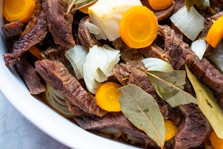 White dish with meat, carrots, onions and laurel.の写真素材
