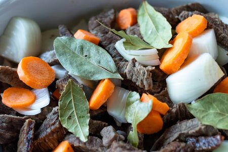 Dish with meat, carrots, onions and laurel on a black pan. の写真素材
