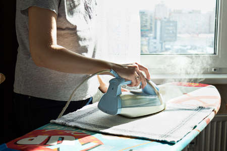 The woman irons clothes on the ironing board. household chores, quarantine