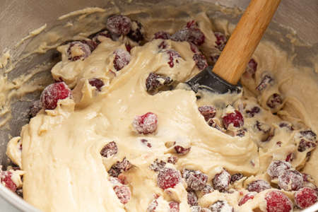 making a bundt cake, a woman adds cranberries to the dough