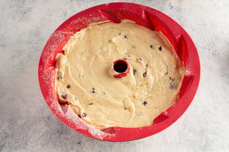 making a bundt cake, a woman adds cranberries to the dough