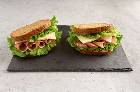 sandwich with ham, cheese and lettuce leaves on a cutting board. Home cookingの写真素材