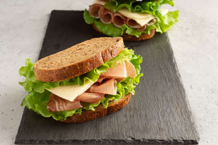 sandwich with ham, cheese and lettuce leaves on a cutting board. Home cookingの写真素材