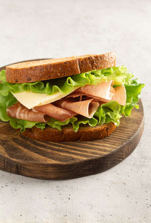 sandwich with ham, cheese and lettuce leaves on a cutting board. Home cookingの写真素材