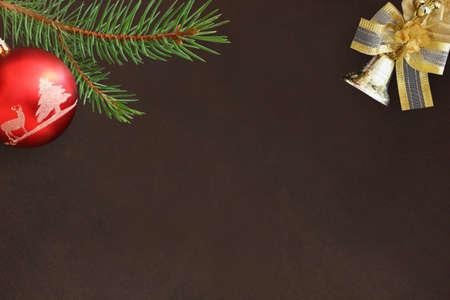 Christmas fir branch, red ball and bell on a dark backgroundの写真素材