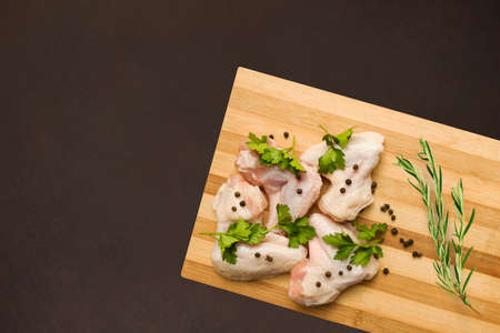 raw chicken wings on a cutting board with spices and rosemary