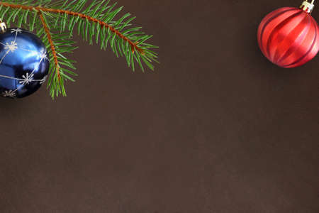 Dark background with Christmas fir branch, blue and red wavy ball