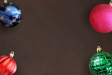 Christmas blue, pink, red wavy and green ribbed ball on dark wooden table. Top view.