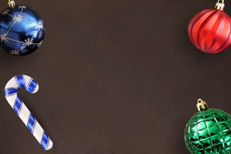 Christmas blue, red, wavy and green ribbed ball, stick on dark wooden table. Top view.
