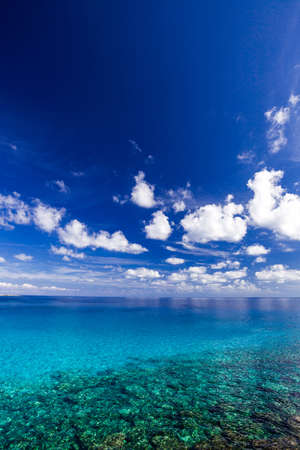 Sea with clear turquoise water and blue sky with clouds on a clear day, vertical frame.の写真素材
