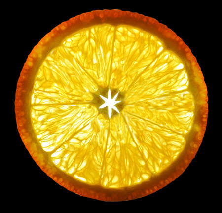 Orange fruit cut a thin transparent piece on a gleam in the background light isolated on black backgroundの写真素材