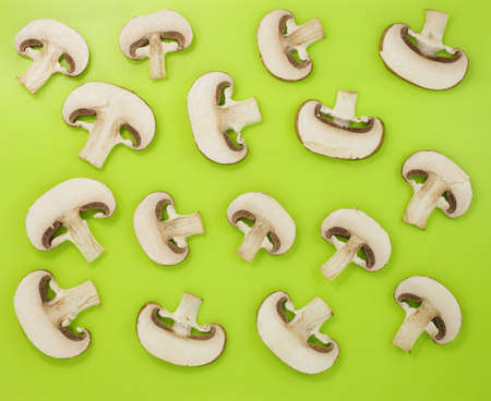 Mushrooms champignons, cut half, many, on a green background, top view.の写真素材