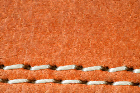 Leather is natural orange, seam is made of white threads, close-up macro viewの写真素材