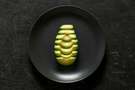 Avocado sliced, one on gray plate, top view dark background.の写真素材