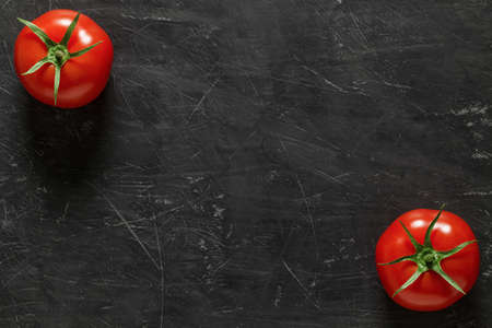 Tomatoes two whole, top view dark background, with space to copy text.の写真素材