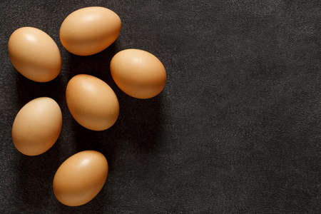 Eggs chicken whole, six pieces, on dark background, top view, space to copy text.