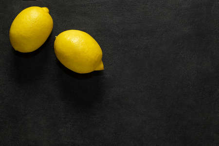 Lemons fresh whole, two pieces, on dark background, top view, space to copy text.の写真素材