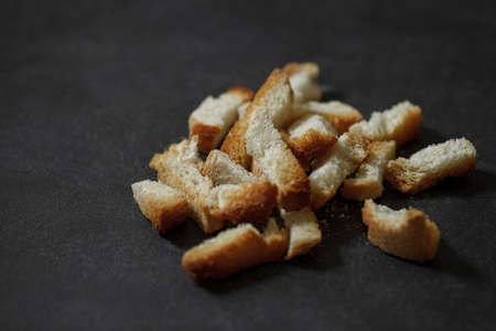 Dried bread rusks cooked, bunch, crumbs, close-up, on dark background, selective focus.