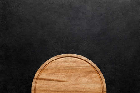 Part of cutting wooden round board on dark background, top view, space to copy text.の写真素材