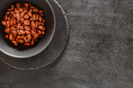 Red beans in dark bowl on slate stone plate round, dark background, top viewの写真素材