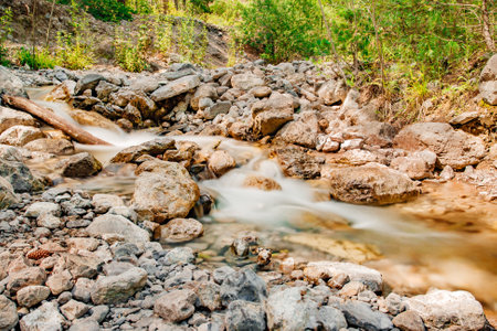 Mountain stream among the rocks in forest, blurred movement of water