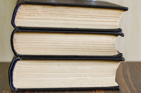 Old books are stacked close-up, three pieces, side view