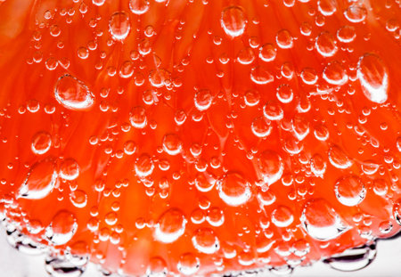 Grapefruit slice peeled pulpy capsules in water with air sphere bubbles, in background light, close-up selective focusの写真素材