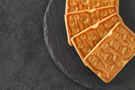 Rectangular sweet crumbly cookies, on slate stone plate round, dark background, top view, selective focusの写真素材