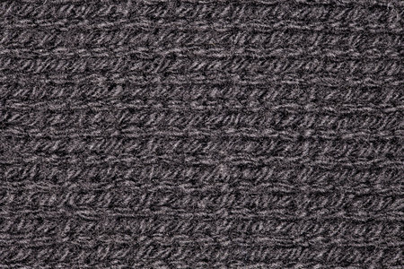Knitted fabric made of yarn threads black close-up, background wallpaper, uniform texture pattern