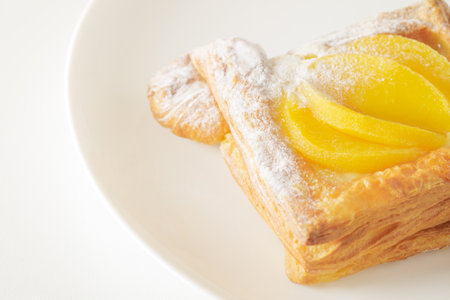 Sweet puff pastry with peaches, cream and powdered sugar, on white plate, top view, selective focusの写真素材
