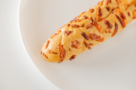 Baguette with baked cheese, on white plate board background, selective focus