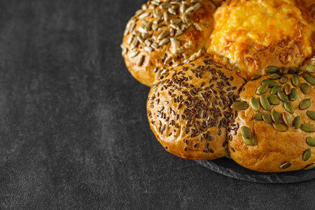 Bun with sunflower seeds flax and pumpkin on slate stone plate round, dark background, selective focusの写真素材