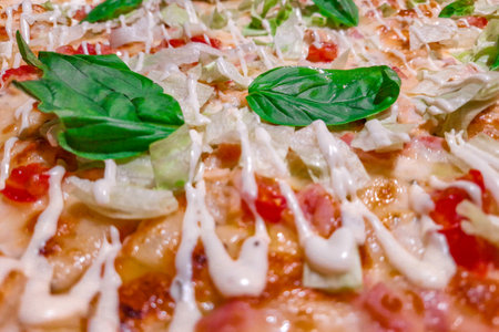 Pizza with cheese ham and basil leaves close-up, selective focusの写真素材