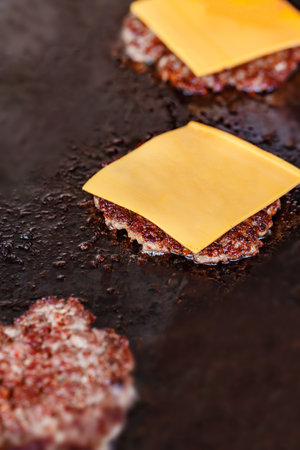 Beef patty chop covered with square piece of cheese fried on baking sheet, close-up, selective focusの写真素材