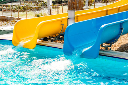 Close-up view of blue and yellow waterslide at aquapark outdoor poolの写真素材