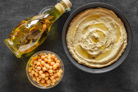 hummus in bowl, olive oil and chickpeas on dark countertopの写真素材