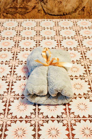 rolled-up towel with a gift ribbon on the tableの写真素材