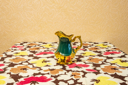 green and gold jug on table with tablecloth