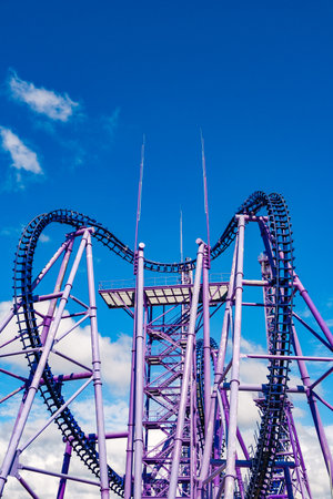 violet metal roller coaster designs against skyの写真素材