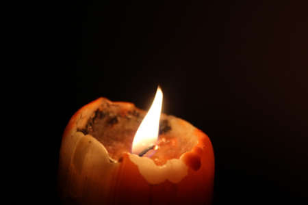 Orange candle with flame in dark backgroundの写真素材